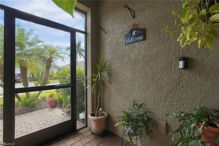 Covered entryway featuring a full-glass storm door, textured stucco wall finish, and brick-paver flooring
