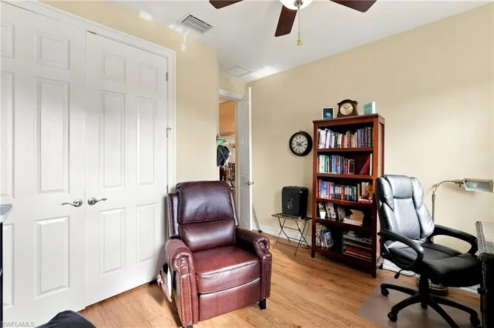 Interior space featuring wood-finish flooring, white paneled double closet doors with brushed nickel hardware, and a ceiling-mounted fan with light fixture