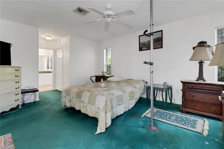 Bedroom with ensuite bathroom, ceiling fan, and dark carpet