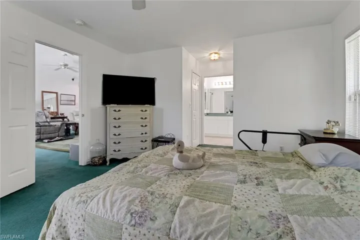 Carpeted bedroom with connected bathroom and ceiling fan