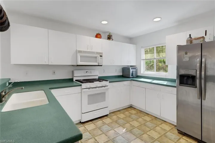 Kitchen with sink, white cabinets, and white appliances