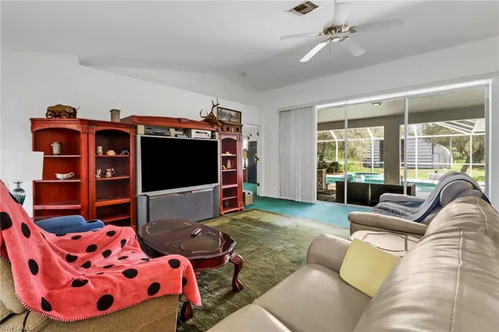 Carpeted living room featuring ceiling fan and lofted ceiling
