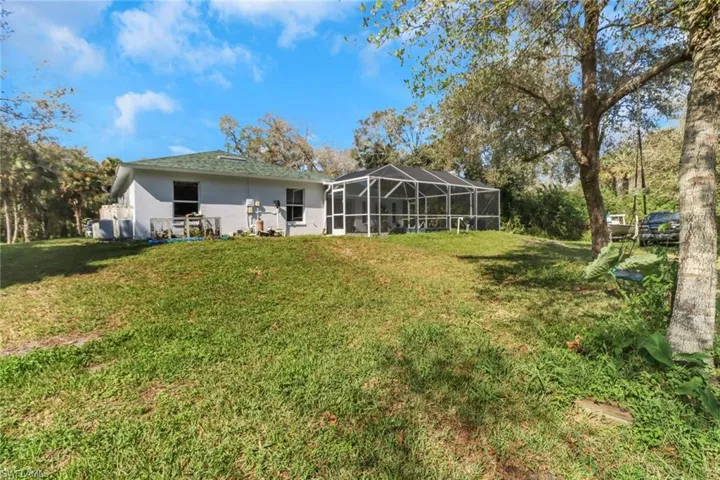 Rear view of property featuring a lanai and a lawn