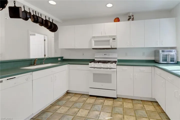 Kitchen with white appliances, white cabinetry, and sink