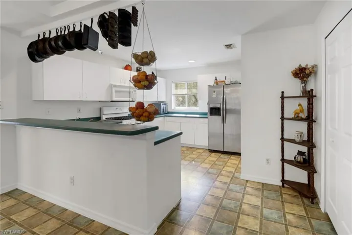 Kitchen with kitchen peninsula, stainless steel appliances, and white cabinetry