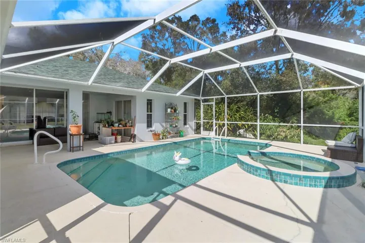 View of pool with glass enclosure, an in ground hot tub, and a patio