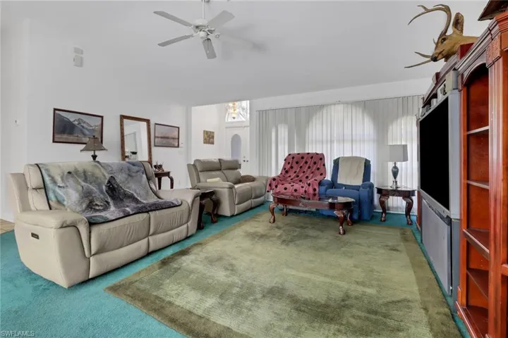Living room featuring dark colored carpet and ceiling fan