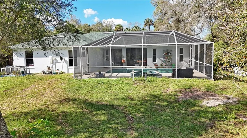 Back of property featuring glass enclosure and a yard