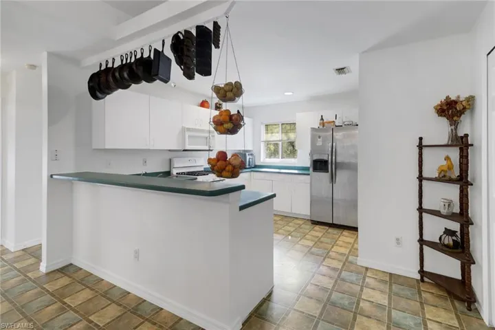 Kitchen featuring white cabinets, white appliances, and kitchen peninsula