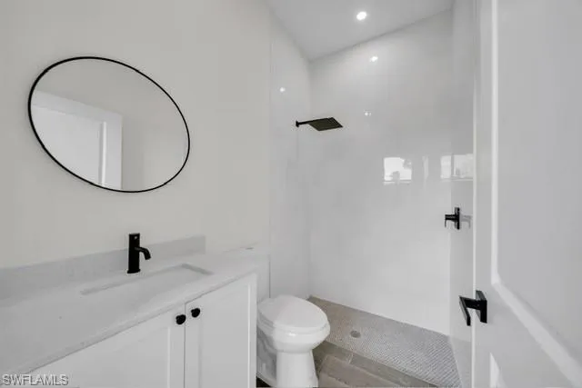 Bathroom featuring vanity, a tile shower, and wood finish floors
