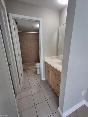 Full bathroom featuring vanity, light tile patterned flooring, and a shower stall