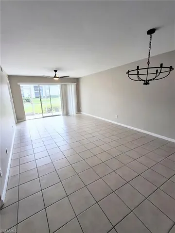 Unfurnished room featuring tile patterned flooring, ceiling fan, and a chandelier