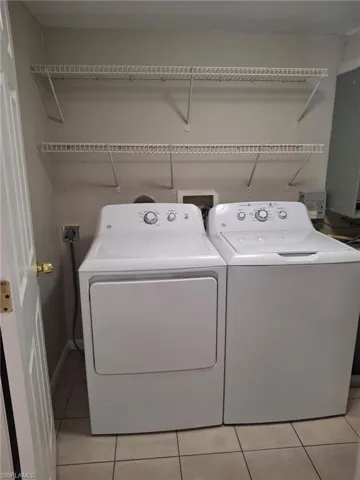 Washroom featuring light tile patterned flooring and washer and dryer