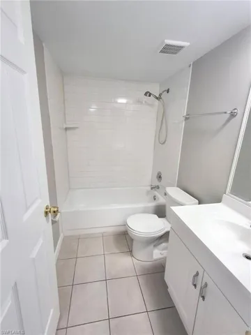 Bathroom with bathtub / shower combination, vanity, and light tile patterned floors