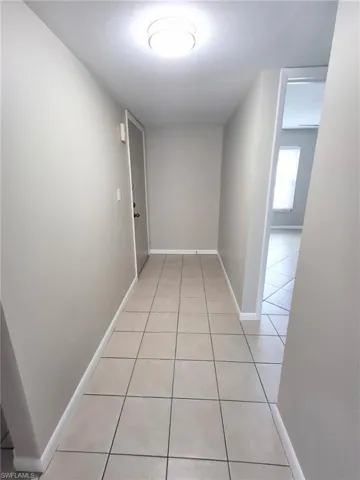 Hall featuring light tile patterned floors and baseboards