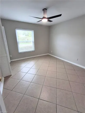 Empty room with light tile patterned floors and ceiling fan