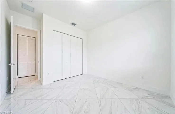 Unfurnished bedroom with a closet and light marble finish floors