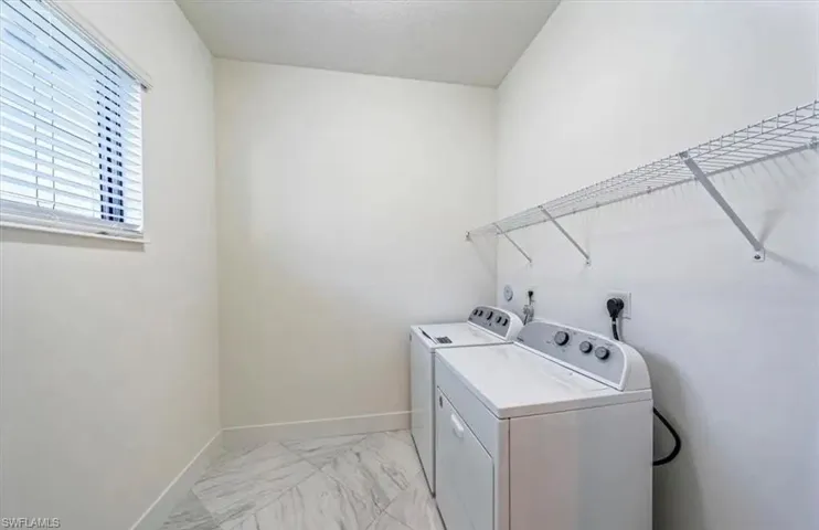 Laundry area featuring light marble finish floors and washer and dryer