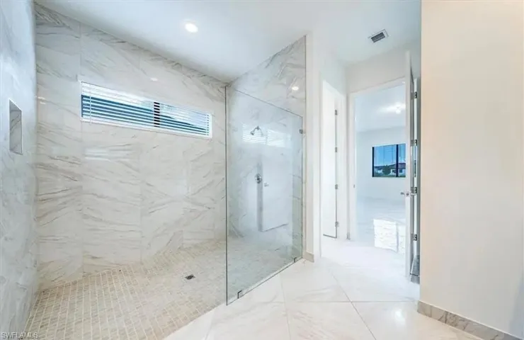 Bathroom featuring a marble finish shower and light marble finish floors