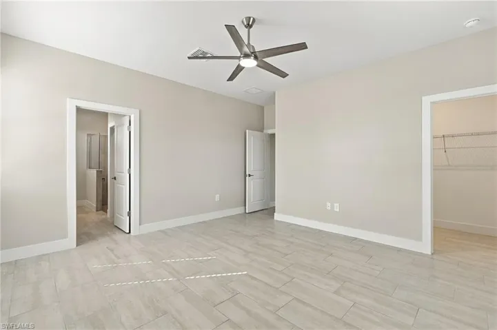 Spacious room featuring tile flooring, neutral wall tones, a ceiling fan, and white trim