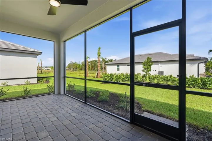 Screened outdoor living area with a ceiling fan, paver flooring, and landscaped perimeter