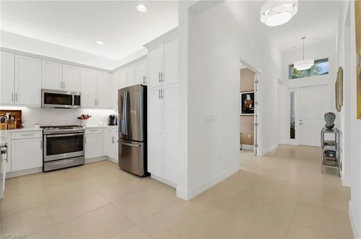 Well- equipped kitchen with stainless steel appliances, quartz countertops & backsplash.