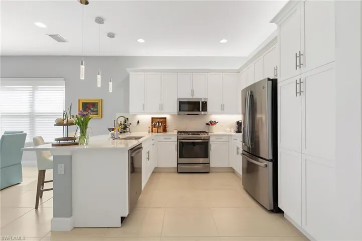 White and bright kitchen features sesigner lighting