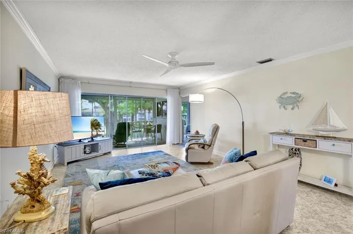 Living area featuring ornamental molding, a ceiling fan, and a textured ceiling