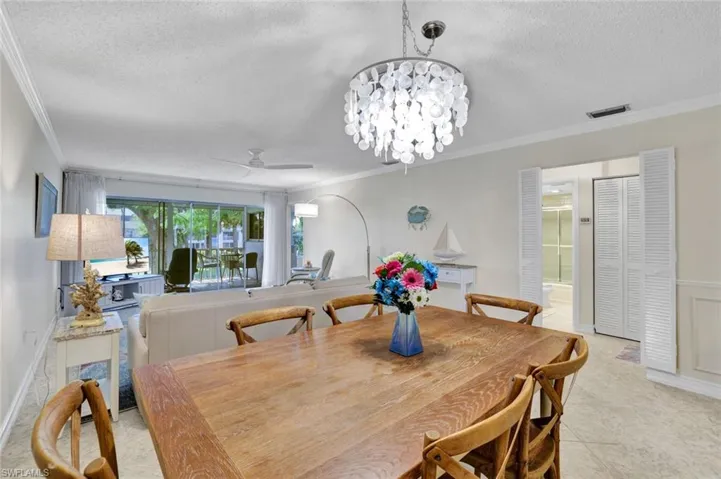 Dining area featuring ceiling fan, ornamental molding, a chandelier, and a textured ceiling