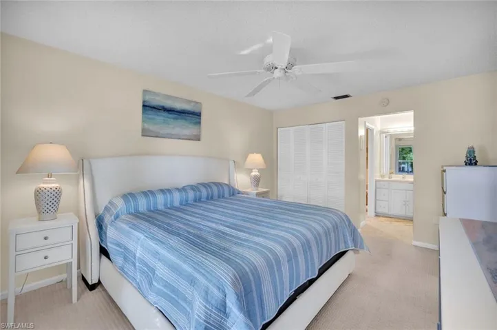Bedroom featuring light carpet, ceiling fan, a closet, and ensuite bathroom