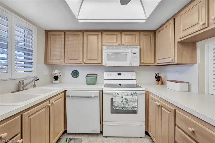 Kitchen featuring white appliances, light countertops, and light brown cabinetry