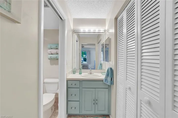 Bathroom with a closet, vanity, and a textured ceiling