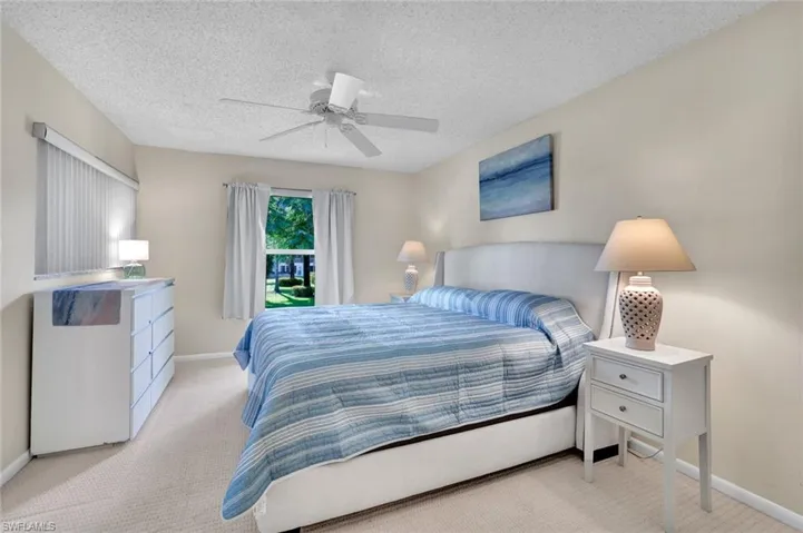 Bedroom with carpet flooring, a textured ceiling, and ceiling fan