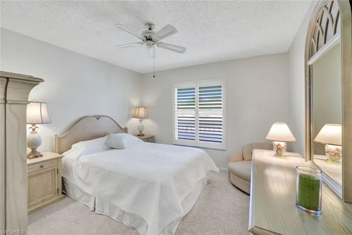 Bedroom with light carpet, a ceiling fan, and a textured ceiling