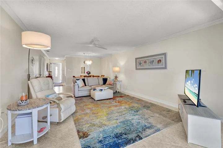 Living room with ornamental molding, a textured ceiling, ceiling fan, and light tile patterned floors