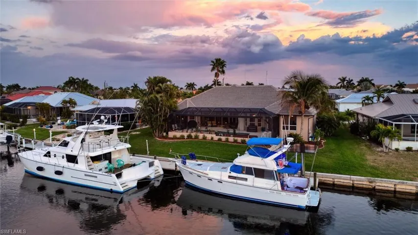 Dock area with a lawn, a water view, glass enclosure, and boat lift