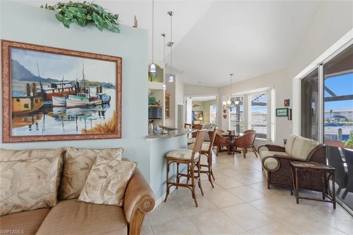 Living room featuring a chandelier, light tile patterned floors, and vaulted ceiling