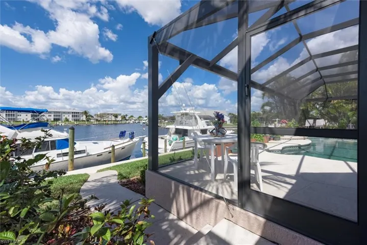 View of patio / terrace featuring a lanai, a water view, an outdoor pool, a sunroom, and a dock