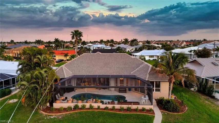 Rear view of house with an outdoor pool, a patio area, a lanai, a sunroom, and a lawn