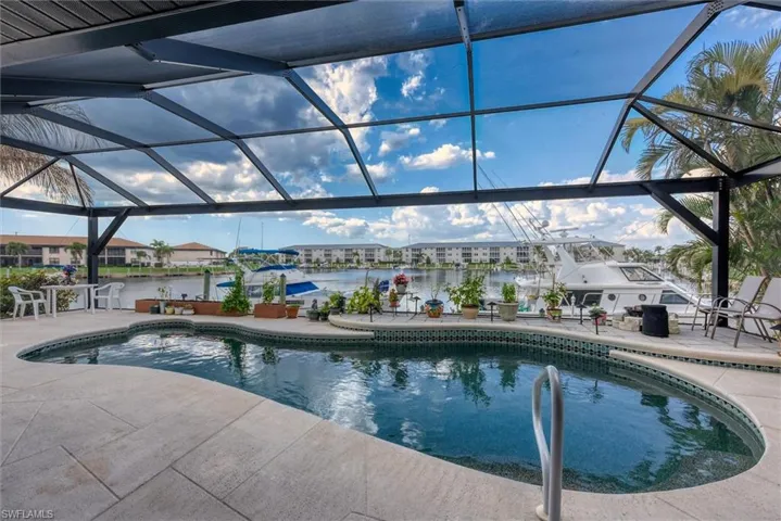 Outdoor pool featuring glass enclosure, a patio area, a sunroom, and a water view