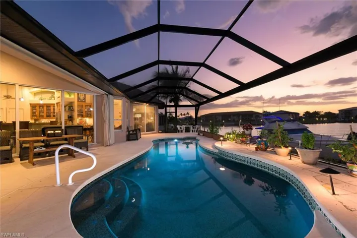 Swimming pool featuring a sunroom, a patio area, and glass enclosure