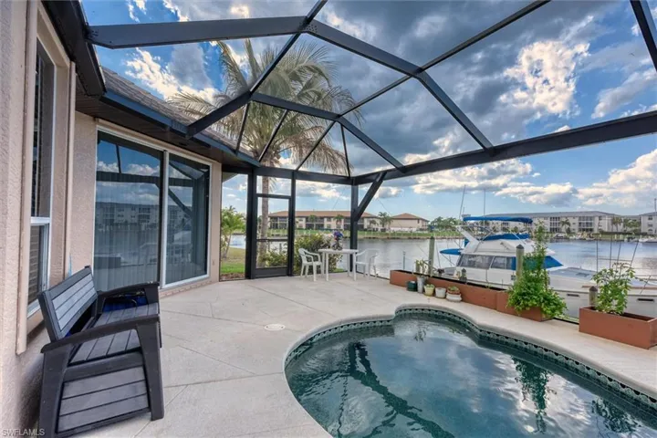 Outdoor pool featuring a patio area, a sunroom, a lanai, a water view, and a dock