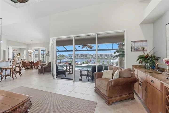 Living area with a sunroom, lofted ceiling, healthy amount of natural light, and light tile patterned floors