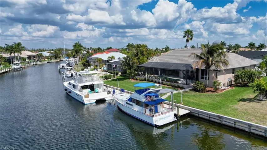Dock area featuring a lawn, a lanai, a water view, boat lift, and a residential view