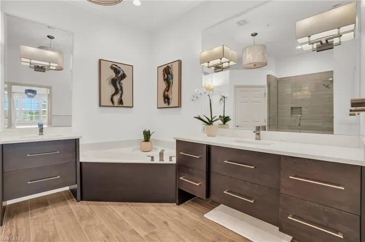 Bathroom featuring hardwood / wood-style flooring, dual bowl vanity, and separate shower and tub