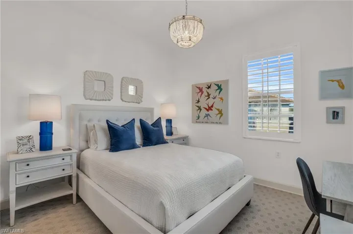 Bedroom with light carpet and an inviting chandelier