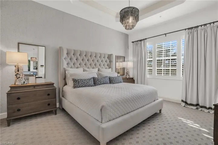 Bedroom featuring carpet floors, a chandelier, and a tray ceiling