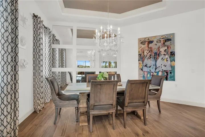 Dining space with hardwood / wood-style floors, a tray ceiling, and a notable chandelier