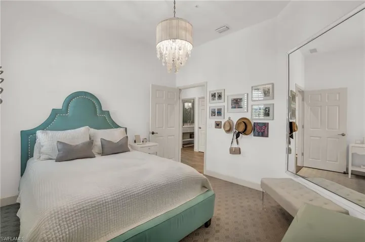 Bedroom featuring a notable chandelier, hardwood / wood-style floors, and a high ceiling