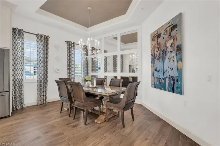 Dining room with a chandelier, wood-type flooring, and a raised ceiling